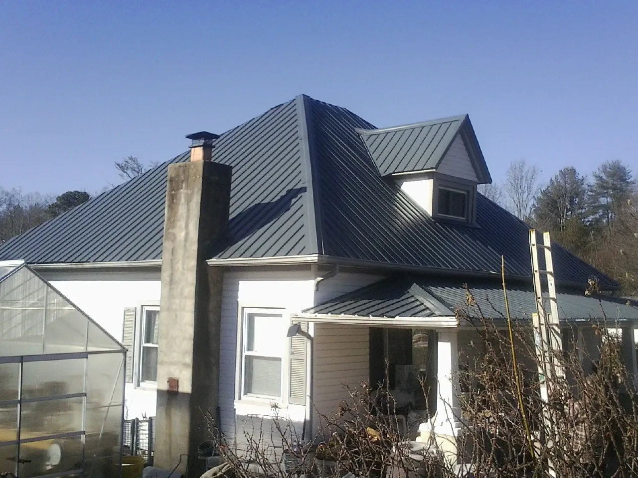 Dark blue standing seam metal roof on a white farmhouse with dormer — Slate & Tile Roof Repair by Roofing Brothers in Gold Beach