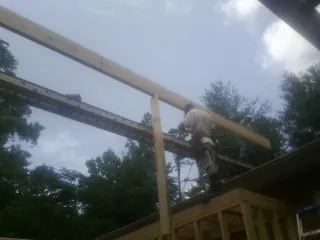 Carpenter setting a ridge beam over a new addition frame — Ice Dam Removal by Roofing Brothers in Gold Beach