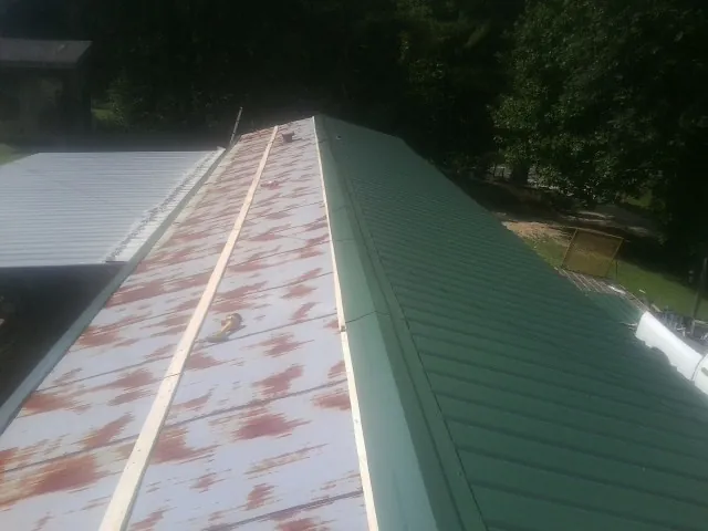 Old rusted panels beside newly installed green metal roofing — Wind Damage Roof Repair by Roofing Brothers in Gold Beach