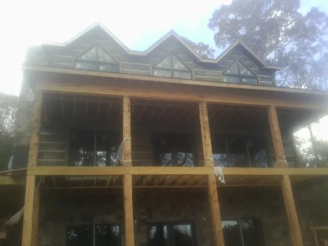 Dormers and porch framing on a large log home under construction — Roof Coating work by our crew in Gold Beach