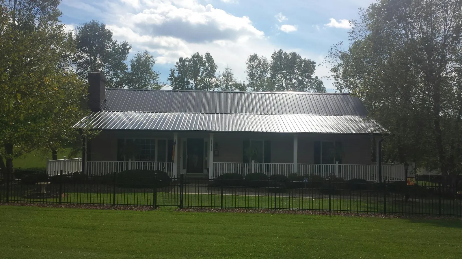 Gray metal roof on a brick ranch with a full width front porch — Gutter Guard Installation work by our crew in Gold Beach