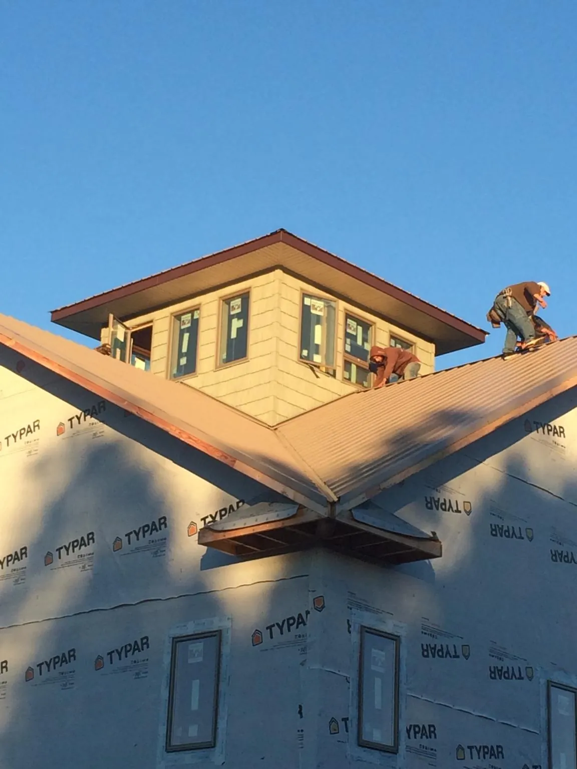 Roofers working around a rooftop cupola on a new metal roof at sunset — Roof Waterproofing in Gold Beach by Roofing Brothers